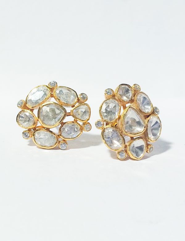 A close-up image of elegant multi stone earrings with clear, polished stones set in gold-plated silver, arranged in a circular design. The intricate details highlight the sparkle of each stone against a white background.