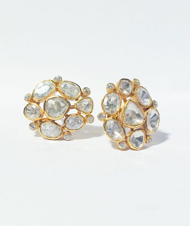 A close-up image of elegant multi stone earrings with clear, polished stones set in gold-plated silver, arranged in a circular design. The intricate details highlight the sparkle of each stone against a white background.